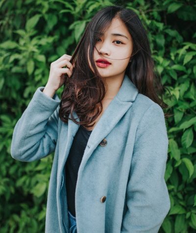 woman in gray coat standing near green plants